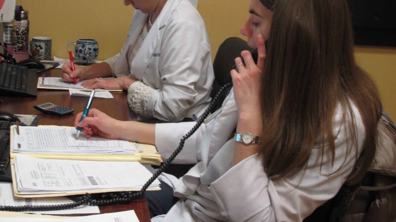 two women writing and talking on the phone